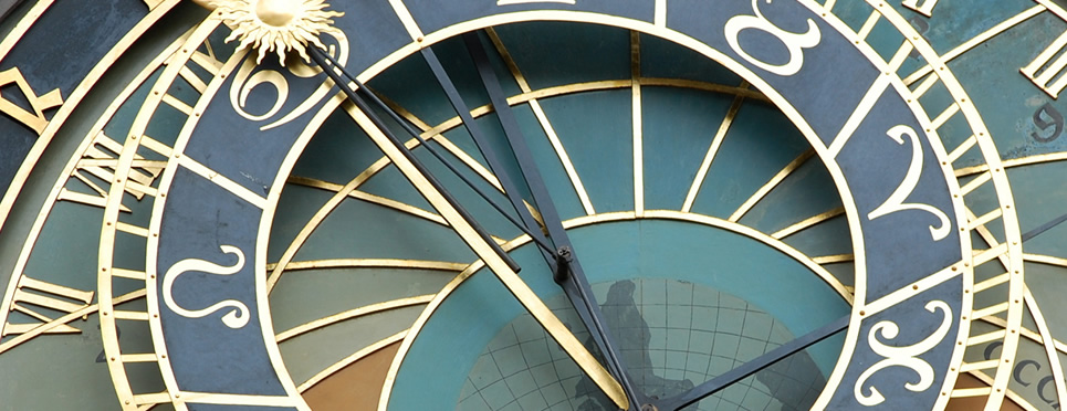 Close-up of golden clock hands on a blue and gold clock face.